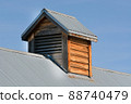 Rural wooden air vent cupola on blue metal roof against blue sky 88740479