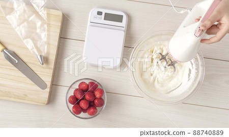 A girl making sweets. Girl's hands mixing whipped cream 88740889