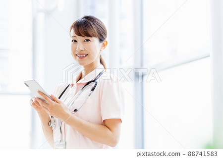 A female medical worker operating a smartphone in the facility 88741583