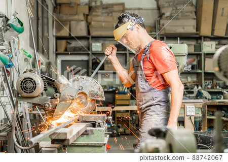 Handyman operating steel cutter machine in workshop 88742067
