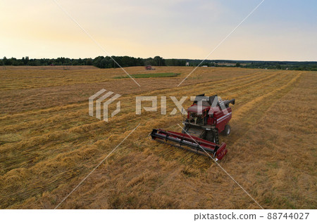 Combine harvester on harvesting oilseed rape in field. Aerial view of harvest season in wheat field. Combine harvester on harvesting oilseed rape in field. Aerial view of harvest season in wheat field. 88744027