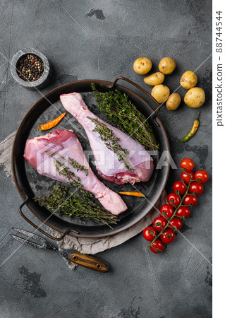Fresh turkey legs with ingredients for cooking, on gray stone table background, top view flat lay, with copy space for text 88744544