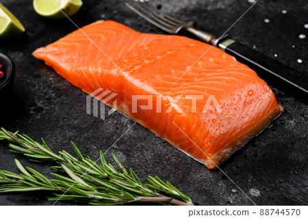 Portioned raw salmon fillet, with herbs, on black dark stone table background Portioned raw salmon fillet, with herbs, on black dark stone table background 88744570