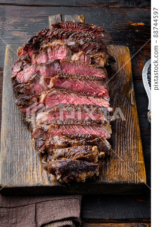 Fresh grilled meat. Grilled beef steak medium rare black angus rib eye steak, on wooden serving board, on old dark wooden table background Fresh grilled meat. Grilled beef steak medium rare black angus rib eye steak, on wooden serving board, on old dark wooden table background 88744597