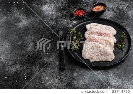 Uncooked Wiener Schnitzel, breaded steak ready to cook, on black dark stone table background, with copy space for text Uncooked Wiener Schnitzel, breaded steak ready to cook, on black dark stone table background, with copy space for text 88744750