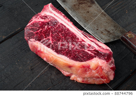 Raw beef meat marbled dry aged Club or striploin on the bone steak, on black wooden table background, with copy space for text 88744796