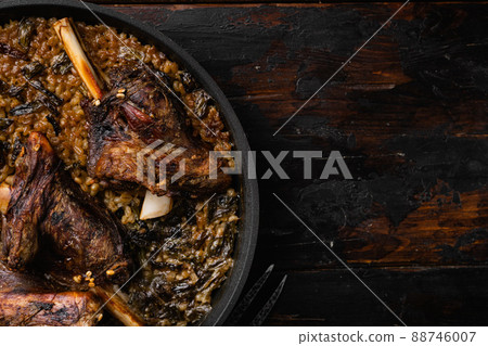 Baked lamb shank with barley and ale, on old dark wooden table background, top view flat lay, with copy space for text Baked lamb shank with barley and ale, on old dark wooden table background, top view flat lay, with copy space for text 88746007
