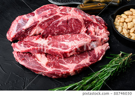 Raw Grass Fed Ribeye Steak with Salt and Pepper and herbs, on black stone background Raw Grass Fed Ribeye Steak with Salt and Pepper and herbs, on black stone background 88746030