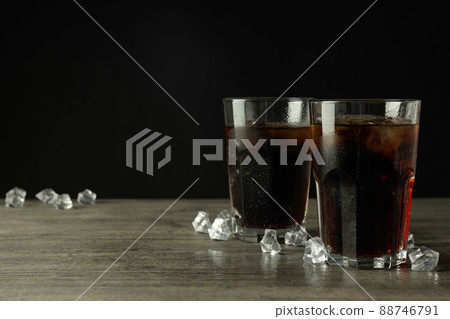 Glass of cola and ice on gray textured table Glass of cola and ice on gray textured table 88746791