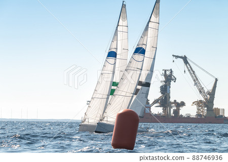 Two sport sailboats next to a turning buoy 88746936