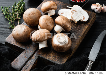 Brown champignons mushroom, on black wooden table background 88747402