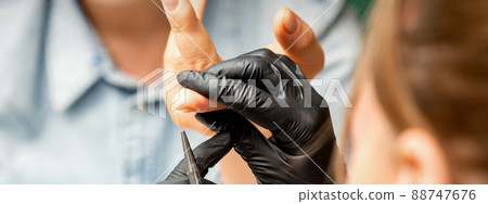 Manicure painting art. Manicure master drawing on the nail tip with a thin brush, close up 88747676