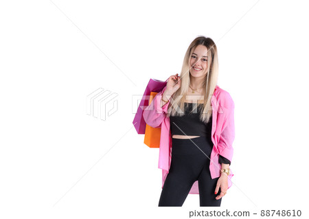 Young woman standing holding shopping bags over her shoulder looking at camera Young woman standing holding shopping bags over her shoulder looking at camera 88748610