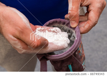 Climber applying chalk powder for rock climbing in bouldering gym.  88749343