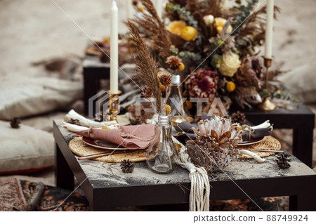 A table designed for a boho style event with an eucalyptus, vintage plates and other rustic touches. On seaside in the sand A table designed for a boho style event with an eucalyptus, vintage plates and other rustic touches. On seaside in the sand 88749924