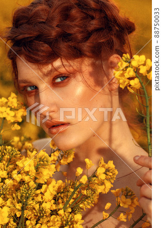 Young fashion model portrait with ginger hair and blue eyes in yellow rapeseed field Young fashion model portrait with ginger hair and blue eyes in yellow rapeseed field 88750033