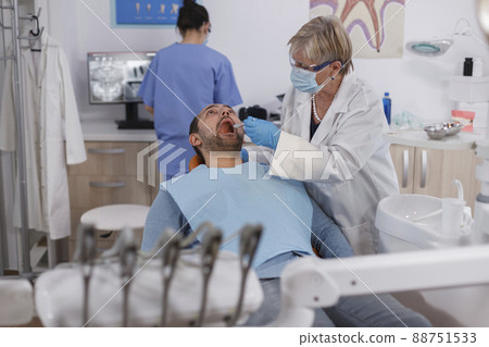 Specialist orthodontist doctor explaining oral hygiene to patient with toothache during dentistry examination in stomatological office room. Dentist working at teeth infection using drill instrument 88751533