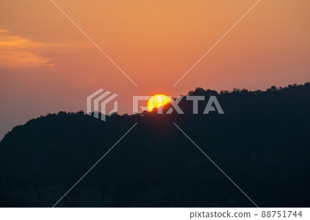 Sunrise behind the mountains, the shadows of the mountains, the orange sky with faint clouds. Sunrise behind the mountains, the shadows of the mountains, the orange sky with faint clouds. 88751744