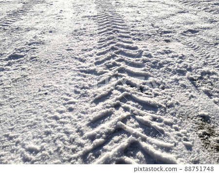 Traces of car tires in the snow in the light of the bright sun. 88751748