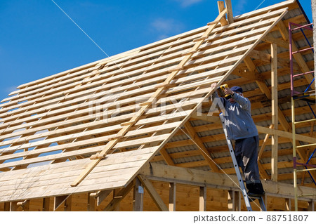 Senior gray-haired builder collects the frame of a wooden country house 88751807