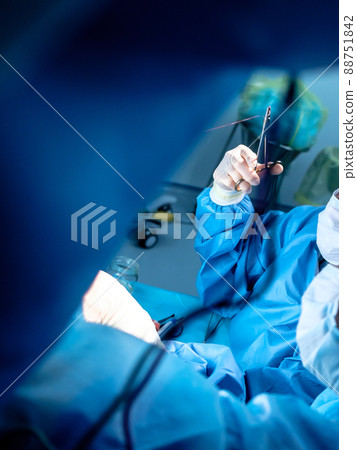 Bloodied hands of surgeons in sterile latex gloves with surgical instruments with traces of blood.  88751842