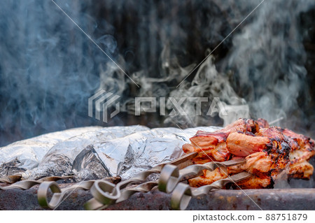 The meat on metal skewers is wrapped in aluminum foil and grilled on charcoal. The meat on metal skewers is wrapped in aluminum foil and grilled on charcoal. 88751879