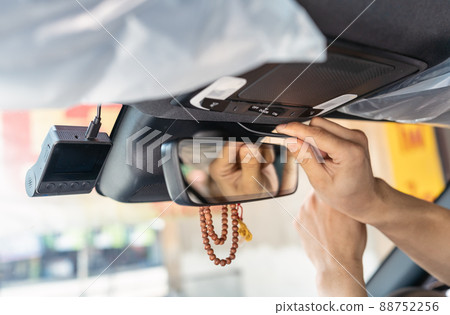 Hand of mechanic prying with installing a front camera car recorder inside a car 88752256