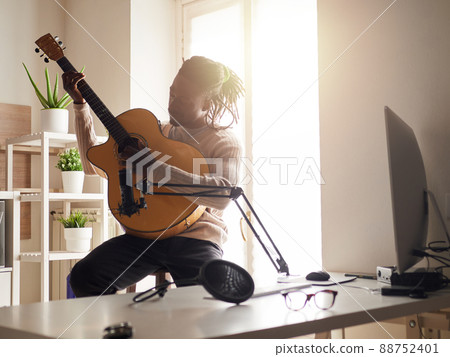 Young man is singing and playing guitar while making an audio recording at home Young man is singing and playing guitar while making an audio recording at home 88752401