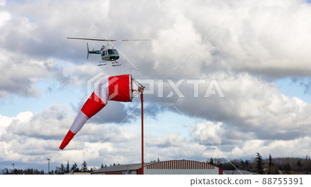 Windsock at an airport with a cloudy sunny sky in background. Windsock at an airport with a cloudy sunny sky in background. 88755391