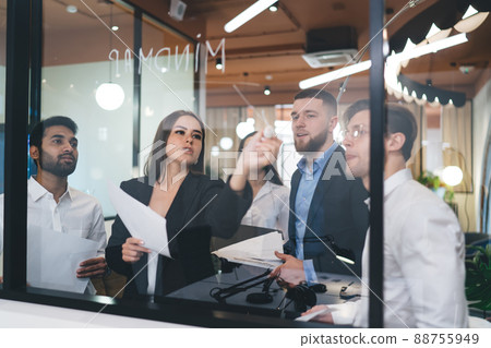 Multiethnic coworkers writing business ideas on glass Multiethnic coworkers writing business ideas on glass 88755949