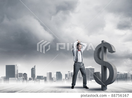 Determined banker man against modern cityscape breaking dollar cement figure 88756167