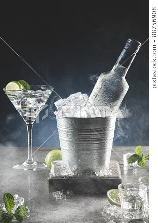Bottle of ice cold vodka in bucket of ice and glasses on dark background with copyspace. Vertical format. Bottle of ice cold vodka in bucket of ice and glasses on dark background with copyspace. Vertical format. 88756908