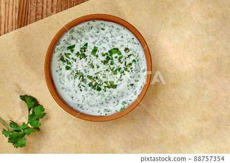 Clay bowl with creamy sauce of matsoni with fresh greens 88757354