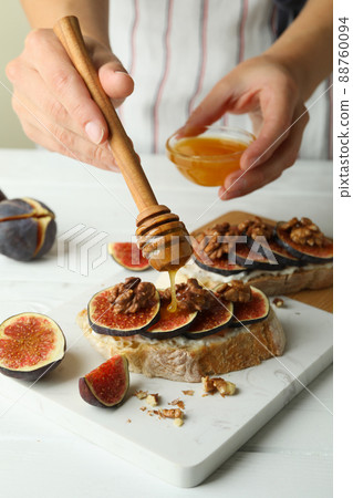 Woman spreads honey on bruschetta with fig Woman spreads honey on bruschetta with fig 88760094