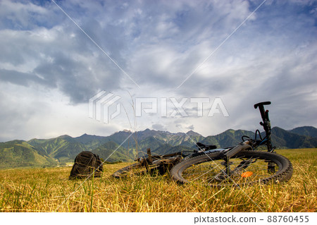 The mountain bike lies on the meadows next to the backpack in the foothills. Bike travel light, copy space 88760455
