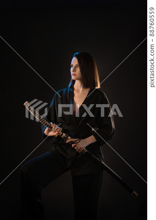 Young beautiful woman in black kimono with katana on black background Young beautiful woman in black kimono with katana on black background 88760559