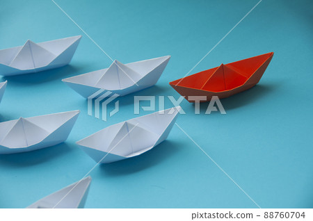 Leadership Concept - Orange color paper ship origami leading the rest of the white paper ship on blue cover background. Copy space concept 88760704