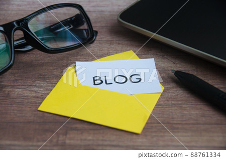 Blog text on small piece of paper in an envelope with office concept background. Online marketing concept Blog text on small piece of paper in an envelope with office concept background. Online marketing concept 88761334
