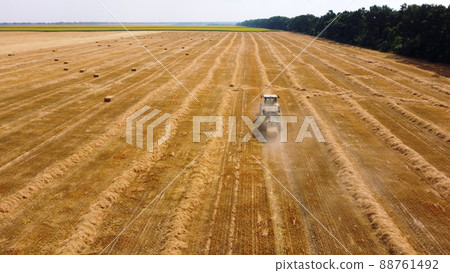 Hay bale tractor. Tractor harvesting hay into bales in field on sunny day. 88761492