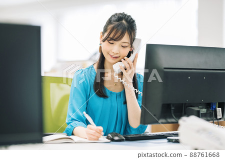 A woman taking notes while calling 88761668