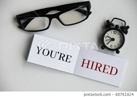 You're hired text on notepad with alarm clock and glasses. 88761824