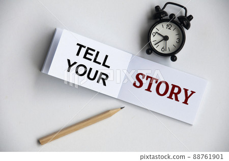 Tell your story text on notepad with alarm clock and pencil on white background. Conceptual Tell your story text on notepad with alarm clock and pencil on white background. Conceptual 88761901