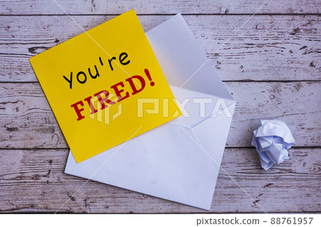 You are fired text on yellow notepad with envelope background. 88761957