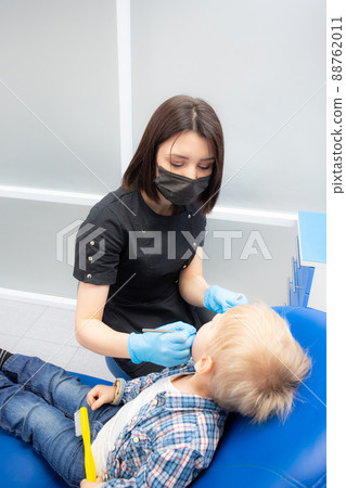 A cute little boy sits at the dentist, opened his mouth, showing his teeth to the dentist. Happy boy is sitting in the dentist's chair. Dentist - young brunette woman A cute little boy sits at the dentist, opened his mouth, showing his teeth to the dentist. Happy boy is sitting in the dentist's chair. Dentist - young brunette woman 88762011
