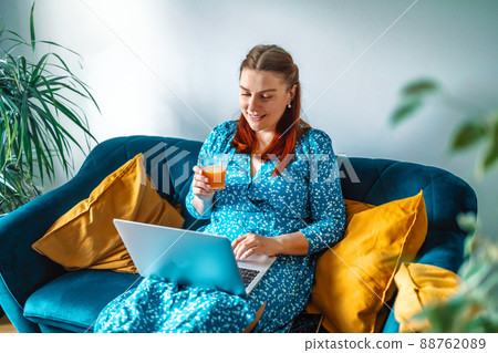Domestic office. Positive 30s female freelancer with fresh juice glass, work on laptop from home at morning Domestic office. Positive 30s female freelancer with fresh juice glass, work on laptop from home at morning 88762089
