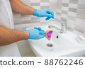 The dentist rinses the dental impression with water under pressure. Close-up of dentist's hands in blue gloves 88762246