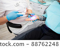 dental office. The dentist shows the child how the ultraviolet lamp works to harden the filling on the arm 88762248