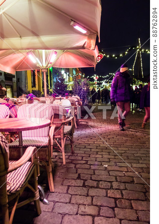 Night cityscape of Copenhagen: Chairs, tables and street people lined up in front of restaurants next to the harbor 88762894