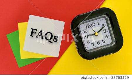 FAQs - message on white notepad. With alarm clock, red and yellow background. Business concept. FAQs - message on white notepad. With alarm clock, red and yellow background. Business concept. 88763339