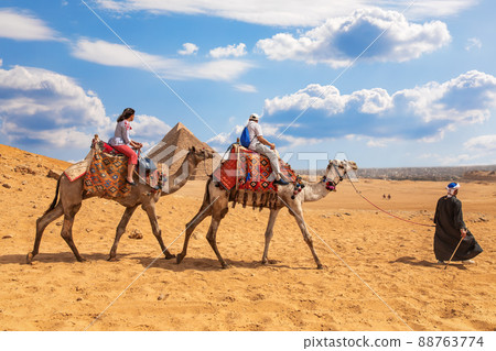 Tourists riding camels near the Pyramids of Giza 88763774